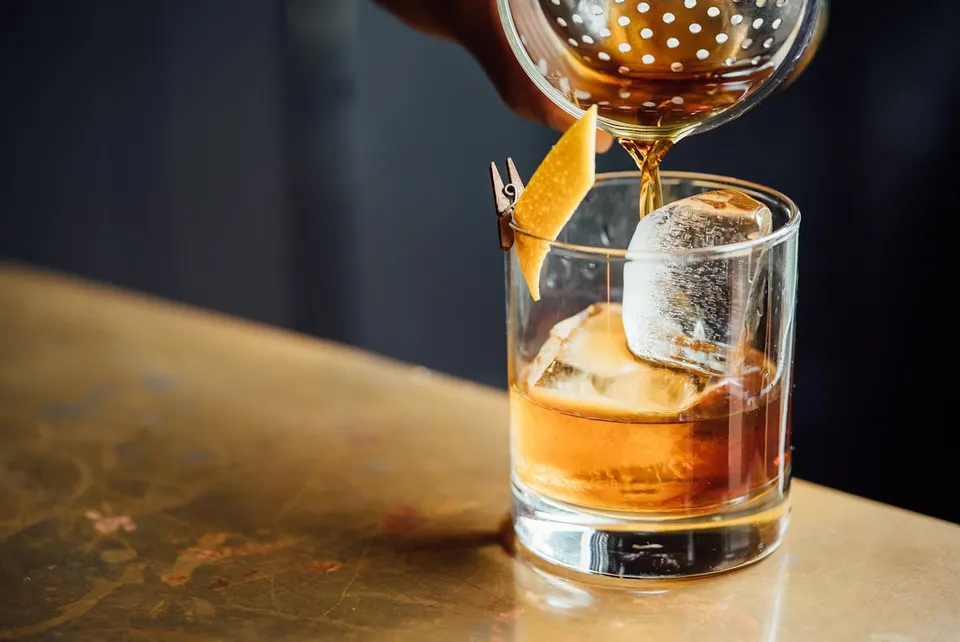 Bartender finishing a cocktail at a busy bar